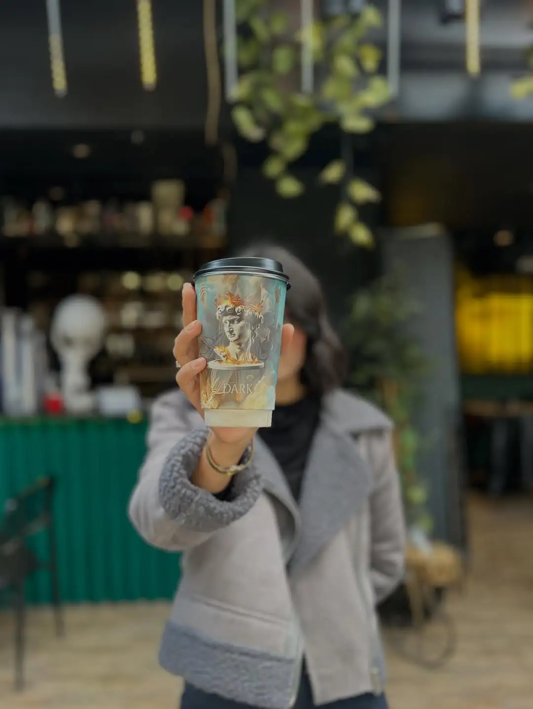 Dark Coffee Factory bardağıyla şehir içinde bir kadraj